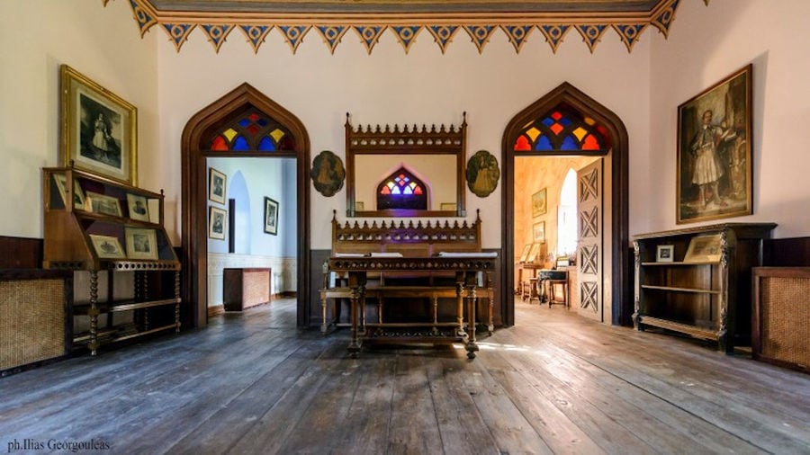 Pyrgos Vasilissis winery room with wooden desk with photo frames and painting on the wall